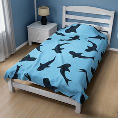 a bed in a bedroom with blue walls and wooden flooring that has black birds on it