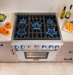 a stove top oven sitting on top of a kitchen counter next to vegetables and wine bottles