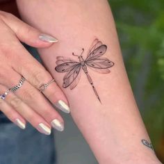 a woman's arm with a small dragonfly tattoo on the left side of her wrist