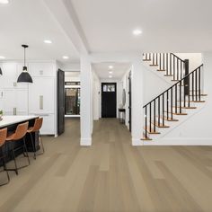 an open floor plan with white walls and wooden floors, black railings and stairs