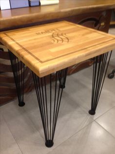 a wooden table with black hairpinks on it and writing on the top that says coffee