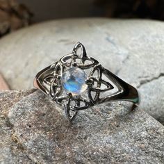 a ring with an opal in the center on top of a rock