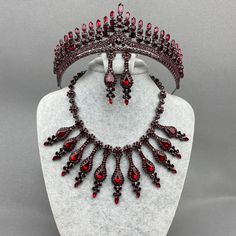 a necklace and earring set with red glass beads on a white mannequin