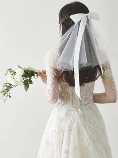 a woman in a wedding dress with a veil on her head and flowers in her hand