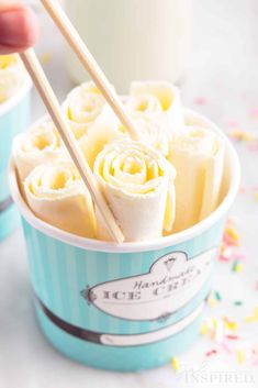 a person holding chopsticks over some food in a cup