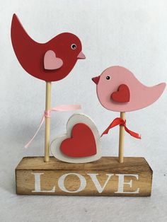 two wooden birds on top of a love sign