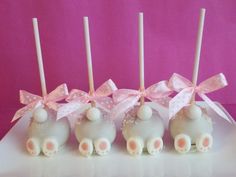 four white cake pops decorated with pink bows and teddy bears on them are lined up in a row