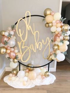 a balloon arch with the word baby spelled out in gold, white and pink balloons