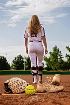 a softball player standing on the field next to a glove and ball