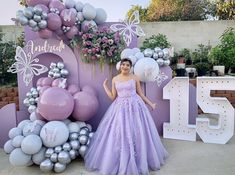 a woman in a purple dress standing next to balloons