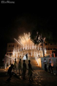 people are standing on the steps in front of a building with fireworks coming from it