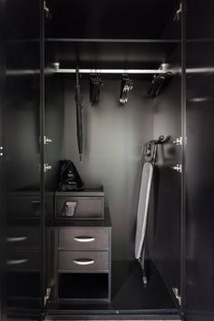 an empty walk - in closet with black walls and silver drawers, two umbrellas hanging on the wall