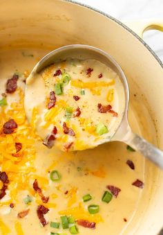 a ladle filled with cheese and bacon soup