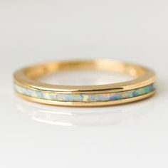 a yellow gold wedding band with opalite inlayed to the side, on a white background