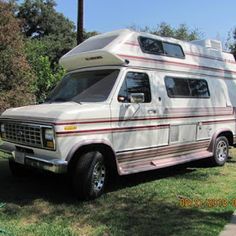 an rv parked in the grass near some trees