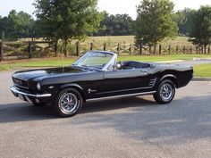 an old black mustang convertible parked in a parking lot