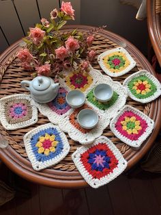 a wicker table topped with lots of crocheted placemats and bowls