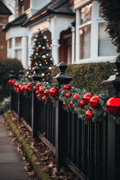 christmas lights are hanging on the fence in front of a house with trees and bushes