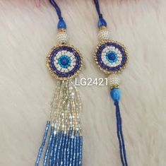 two blue and white beaded tassels with evil eye charms on top of it