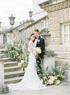 a bride and groom pose for a photo in front of the stairs at their wedding