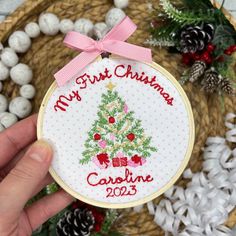 someone holding up a cross stitch christmas ornament