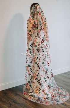 the back of a woman's wedding dress, with flowers on it and a veil over her head