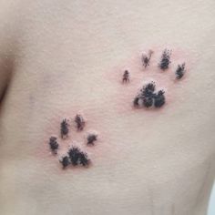 a woman's stomach with black ink on her chest and paw prints all over it