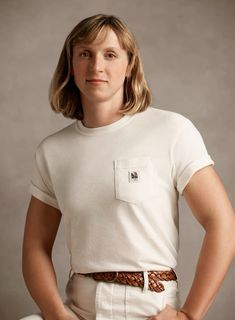 a woman with her hands on her hips wearing a white t - shirt and tan pants