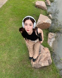 a woman wearing headphones standing on top of a rock