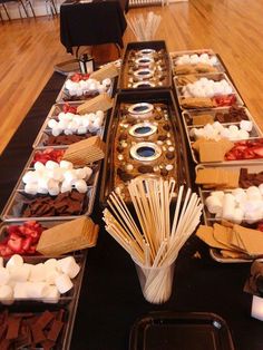 an assortment of desserts and marshmallows displayed on a long buffet table