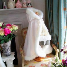 a white fur coat sitting on top of a chair in front of a fire place