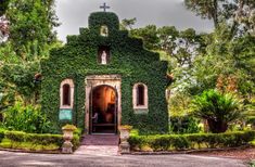 an old church covered in ivy with a cross on top