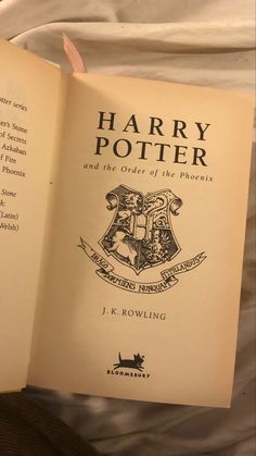 an open harry potter book sitting on top of a bed