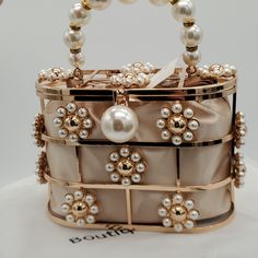 This Beautiful Handbag Is Brand New And Has Never Been Used. I Just Love It! It Is A Fully Functional Bag / Purse It Has Magnetic Closure And A Beautiful Satiny Sack With Pearl Detailed Draw Strings To Keep Your Belongings Privatly Together Inside It Is A Gorgeous Statement Piece To Any Gown Or Party Or Wedding Dress It Can Also Be Used As A Statement Piece In Any Room. It Is Truly Gorgeous And I Hate To Part With It I Simply Have Never Used It And I Am A Bit Of A Pack Rat. Measurements Are 7.07 In Length 3.14 Depth 5.11 Height Happy Poshing! Party Bucket Bag With Gold-tone Hardware, Gold Top Handle Bag For Spring, Spring Evening Rectangular Bags, Spring Party Bags With Removable Pouch, Beige Bags With Pearl Handle For Spring, Spring Party Shoulder Bag With Pearl Handle, Spring Party Bags With Pearl Handle, Cream Bags With Pearl Handle For Spring, Spring Evening Pouch Bag