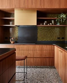 a kitchen with wooden cabinets and black counter tops, along with a brown bar stool