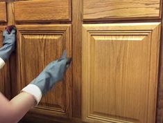 a woman in blue gloves cleaning wooden cabinets