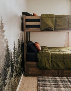 two bunk beds in a small room with trees on the wall and rugs around them