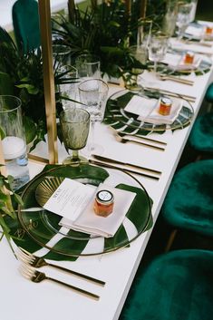 a table set with green velvet chairs and gold chargers