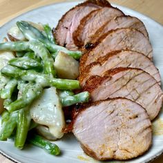 a plate with meat, green beans and potatoes on it