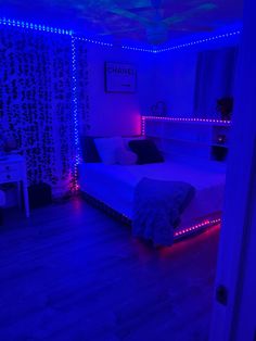 a bedroom with blue lights on the walls and wood flooring, along with a bed