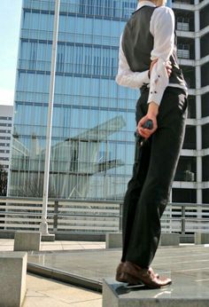 a man standing on top of a cement block in front of a tall glass building