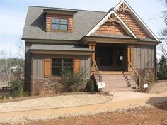 a house that is in the middle of some dirt and has wooden trim on it