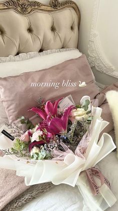 a bouquet of flowers sitting on top of a bed next to a pillow and pillows