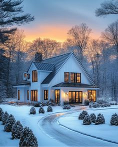 a white house in the middle of winter with snow on the ground and trees around it