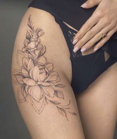 a close up of a woman's thigh with tattoos on it and flowers in the middle