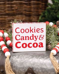 a sign that says cookies, candy and cocoa on top of an old fashioned suitcase