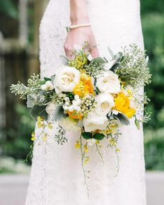 a bridal holding a bouquet of yellow and white flowers