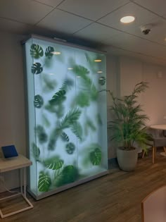 an office cubicle with glass doors and plants on the wall in front of it