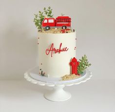 a white cake decorated with red trucks and plants on top of a plate that says anchou