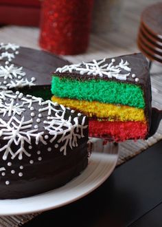 there is a chocolate cake with rainbow frosting on the top and one slice missing